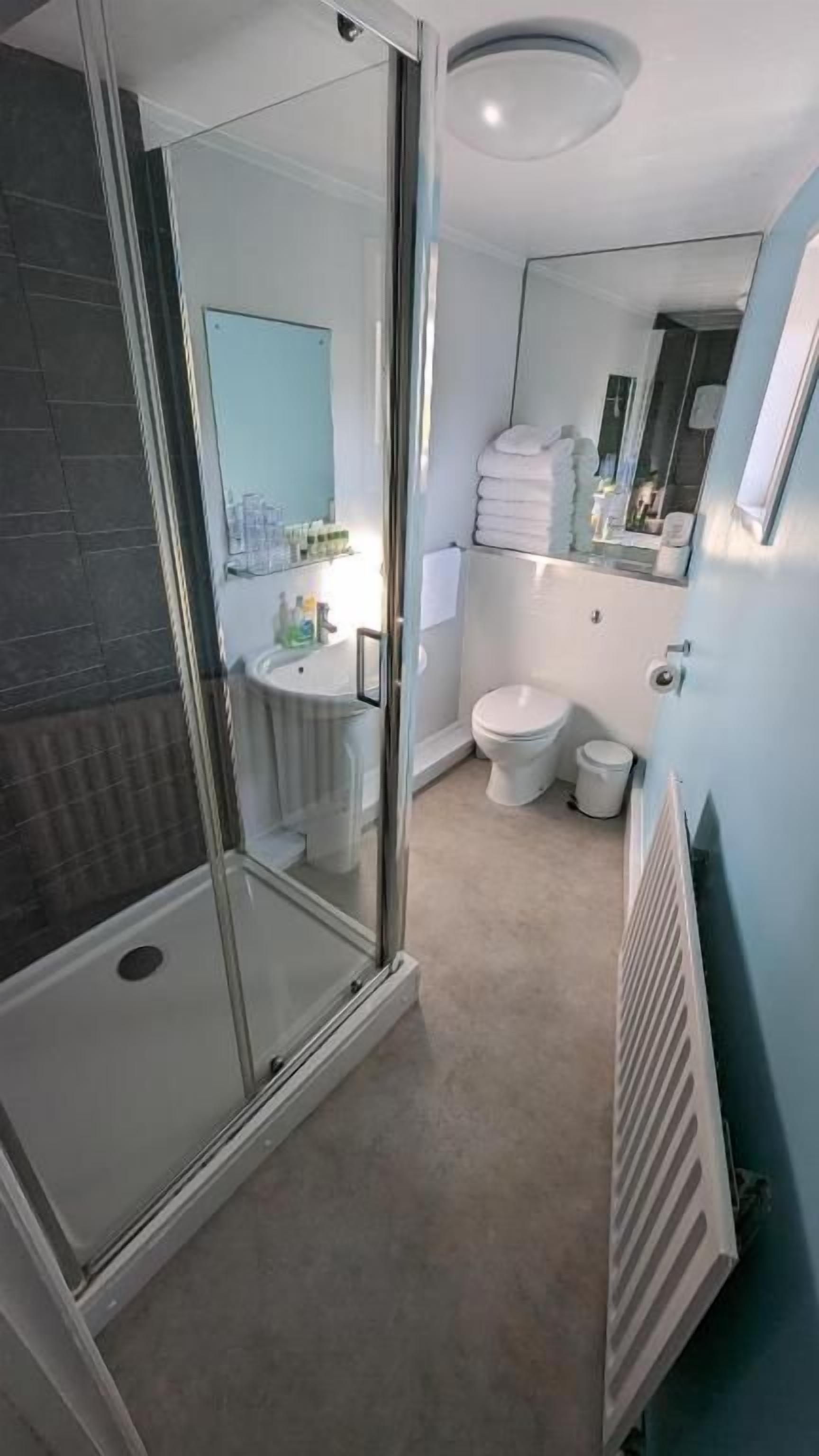 Un baño moderno con cabina de ducha de vidrio, inodoro y lavamanos.