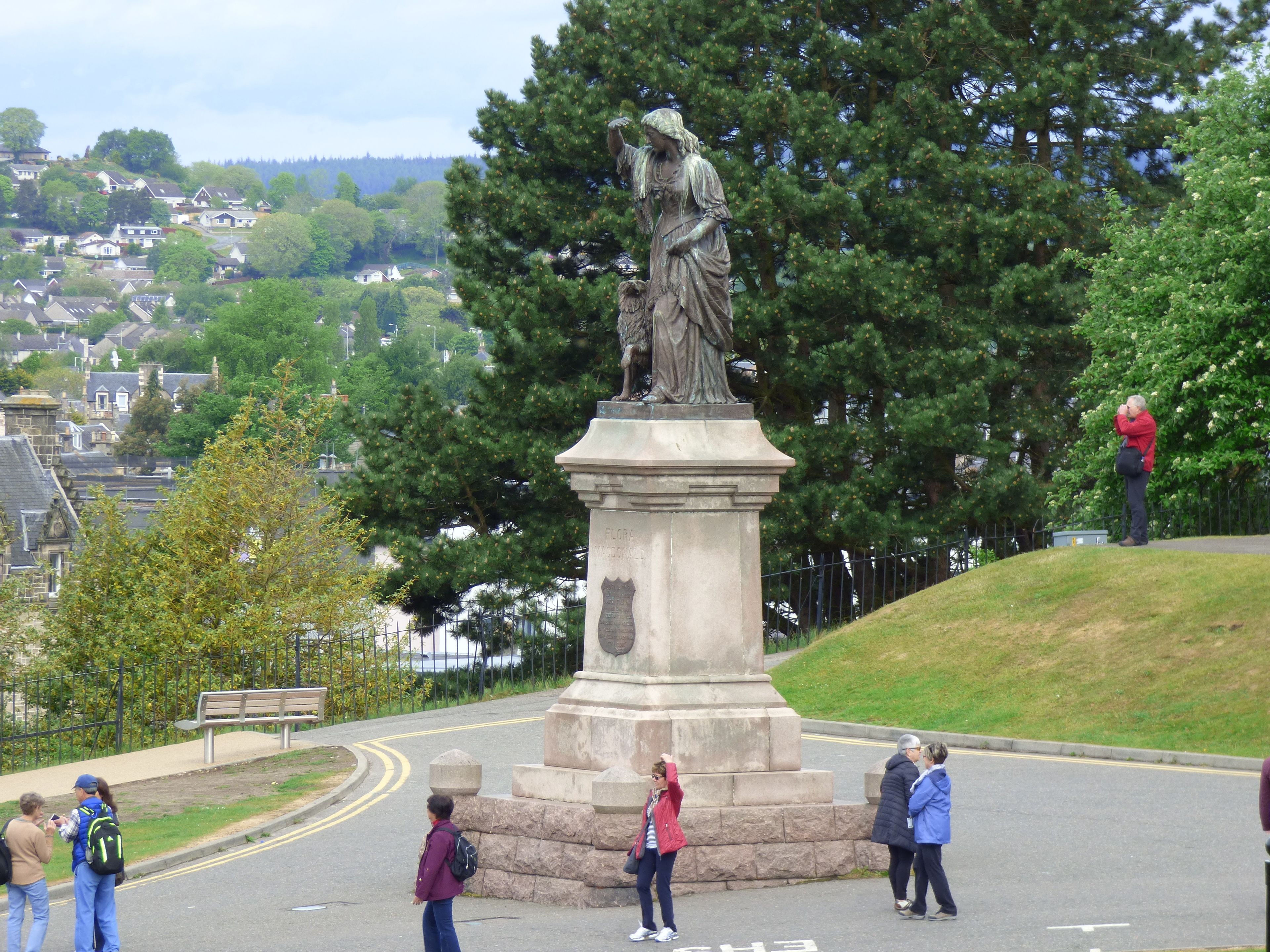 A statue on a pedestal with a town in the background.