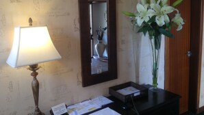 A desk with a lamp, a vase of flowers, a mirror, and a wooden door. - Ardentorrie Guest House (Inverness)