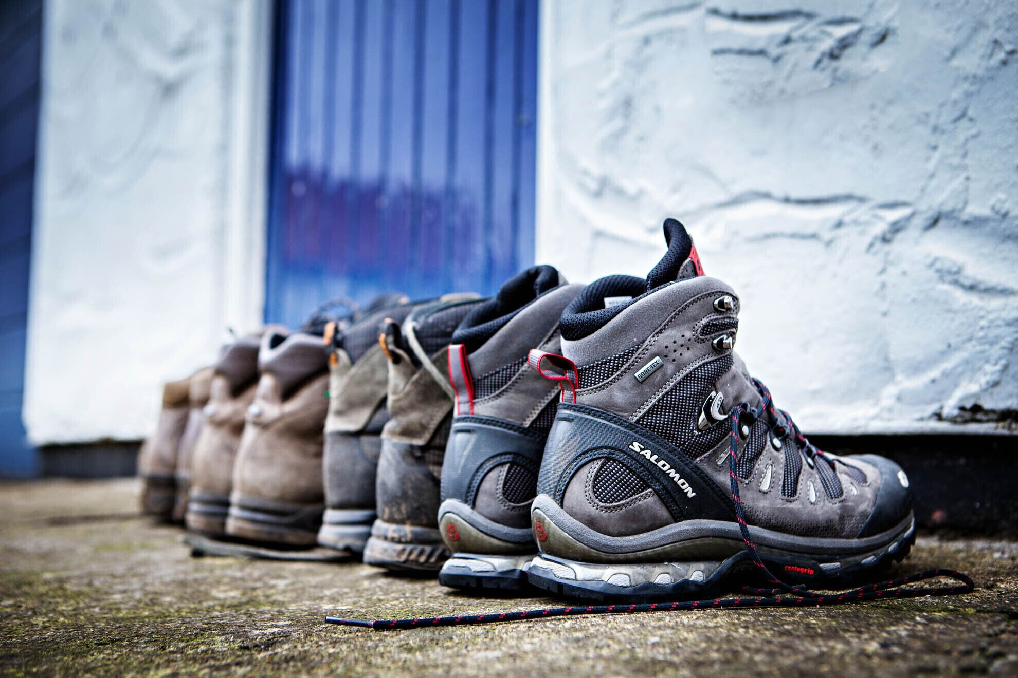 A row of hiking boots lined up against a wall.