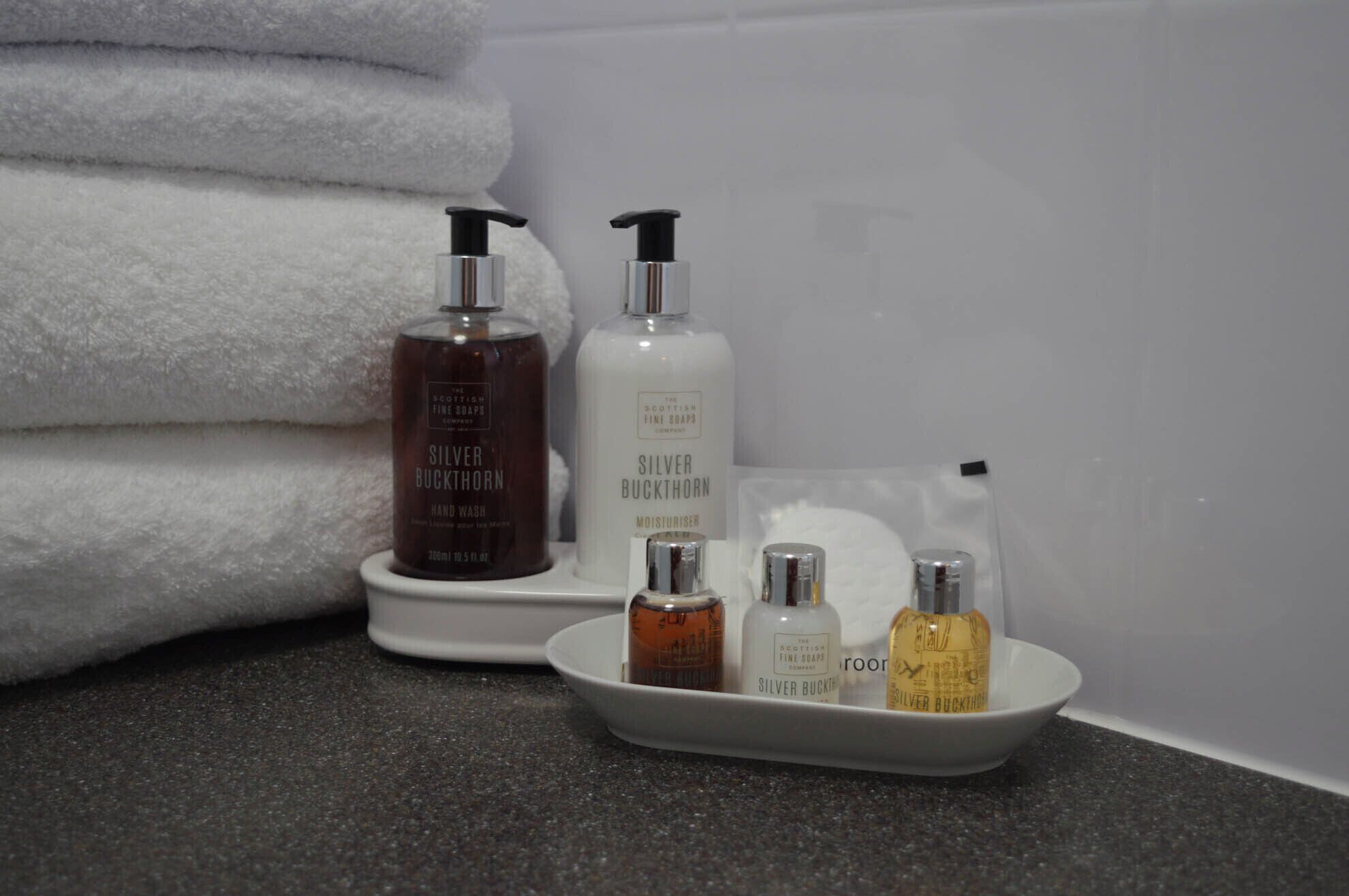 Un baño con artículos de aseo, incluyendo jabón de manos, crema hidratante y una pequeña botella de gel de ducha.