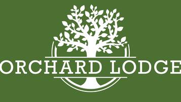 Un logotipo con un árbol estilizado y el texto "ORCHARD LODGE".