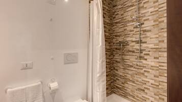 Un baño moderno con ducha, inodoro y barra para toallas.