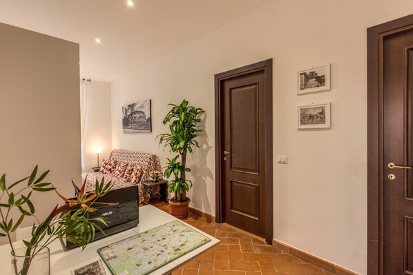 A room with a bed, a table with a map, a potted plant, and a door.