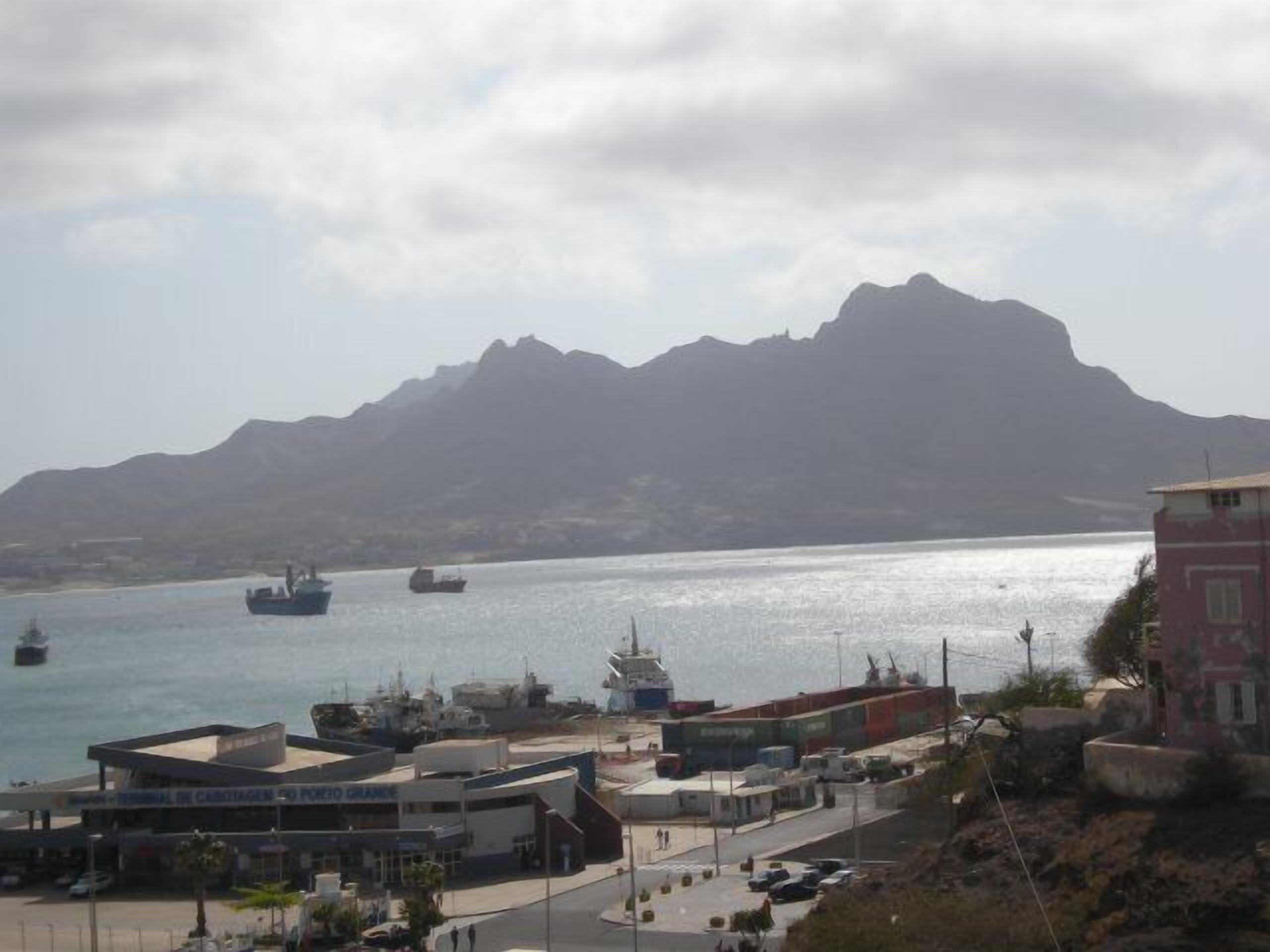 A coastal town with a marina, buildings, and a mountain in the background.