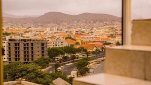 Paisagem urbana com um edifício em destaque no primeiro plano e uma cordilheira ao fundo.