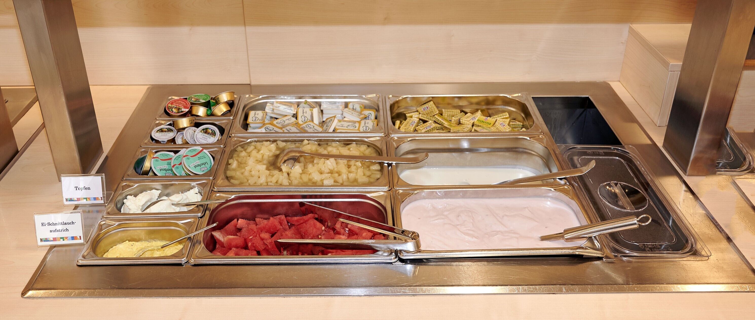 Un bufé con diversos alimentos, incluyendo yogur, queso y frutas.