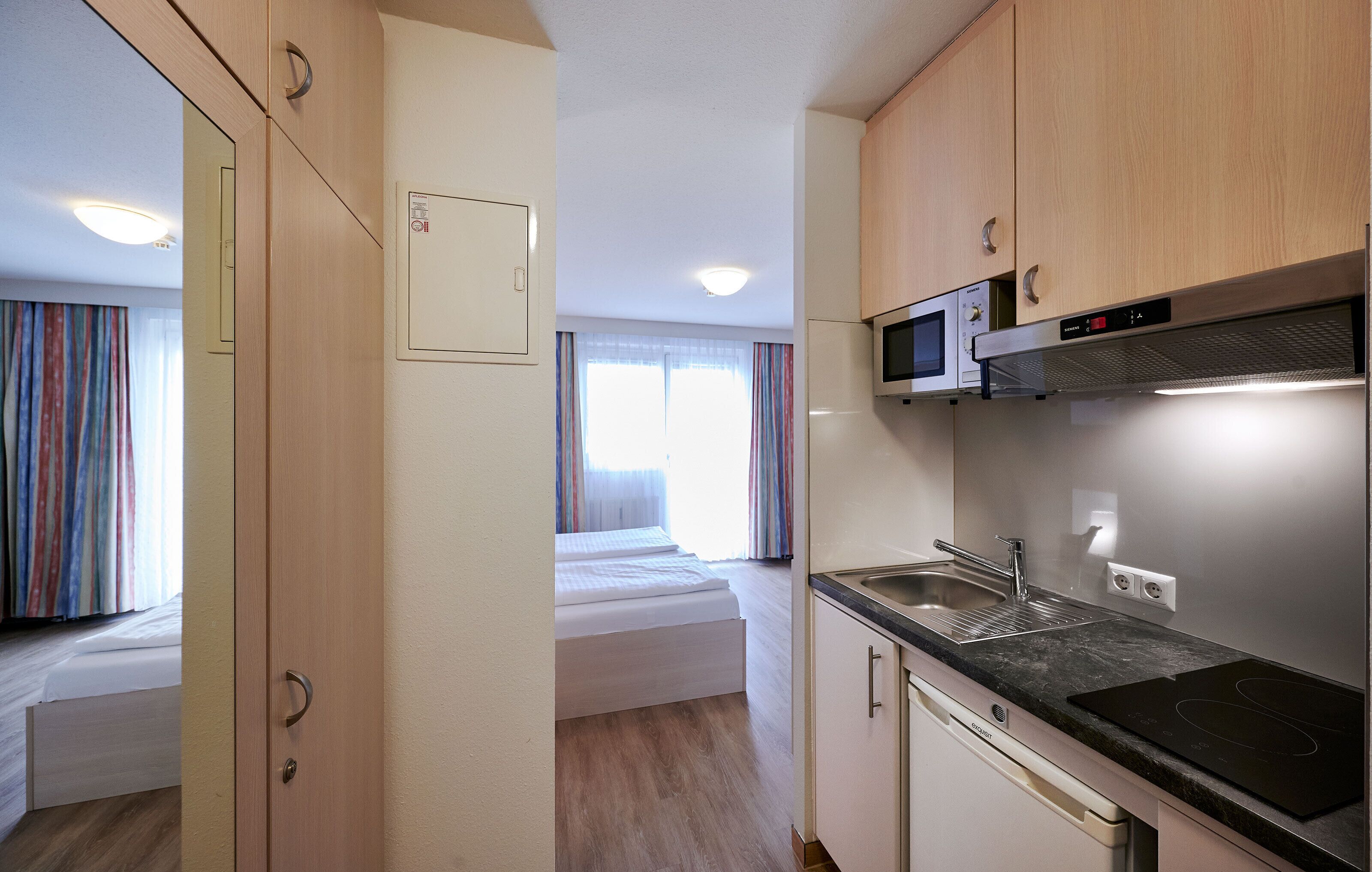 A compact kitchenette with a microwave, sink, and stove.