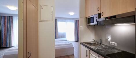 A compact kitchenette with a microwave, sink, and stove.