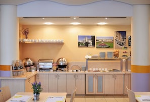 Ein Frühstücksbuffet mit Teegedeck, einer Kaffeemaschine und einer Obstauslage.