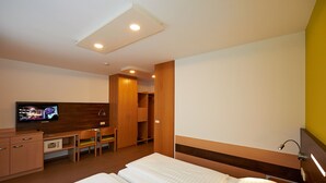 A hotel room with a bed, a desk, a television, and a wardrobe. - Hotel Kolpinghaus Wien Zentral (Vienna)