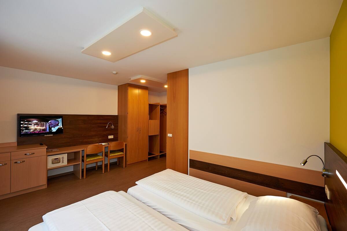 Ein Hotelzimmer mit Bett, Schreibtisch, Fernseher und Kleiderschrank.
