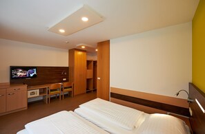 Een hotelkamer met een bed, een bureau, een televisie en een kledingkast.