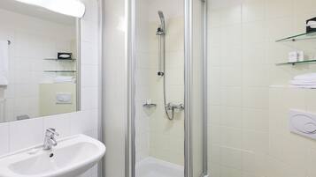 A modern bathroom with a glass-enclosed shower, a white sink, and a toilet.