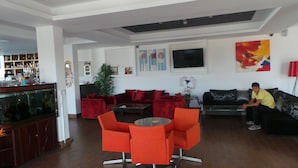A modern living room with red and black furniture, a large fish tank, and a flat-screen TV on the wall. - Neptune Hotel Apartments (Pegeia)