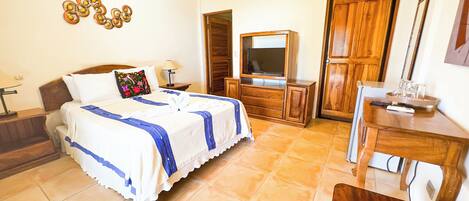 Une chambre d’hôtel avec un lit, une télévision, une commode en bois et un bureau.
