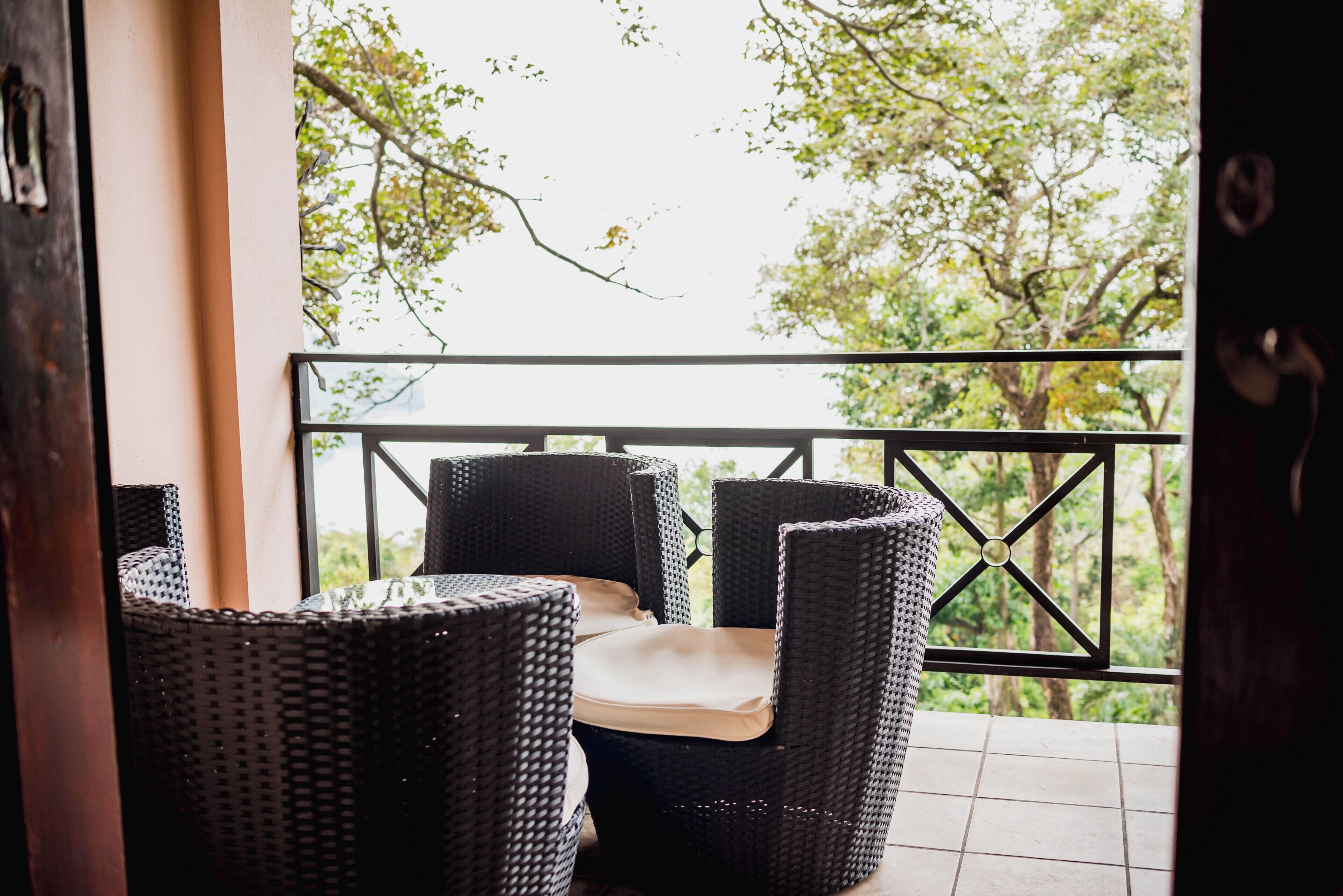 A balcony with wicker furniture and a view of trees.