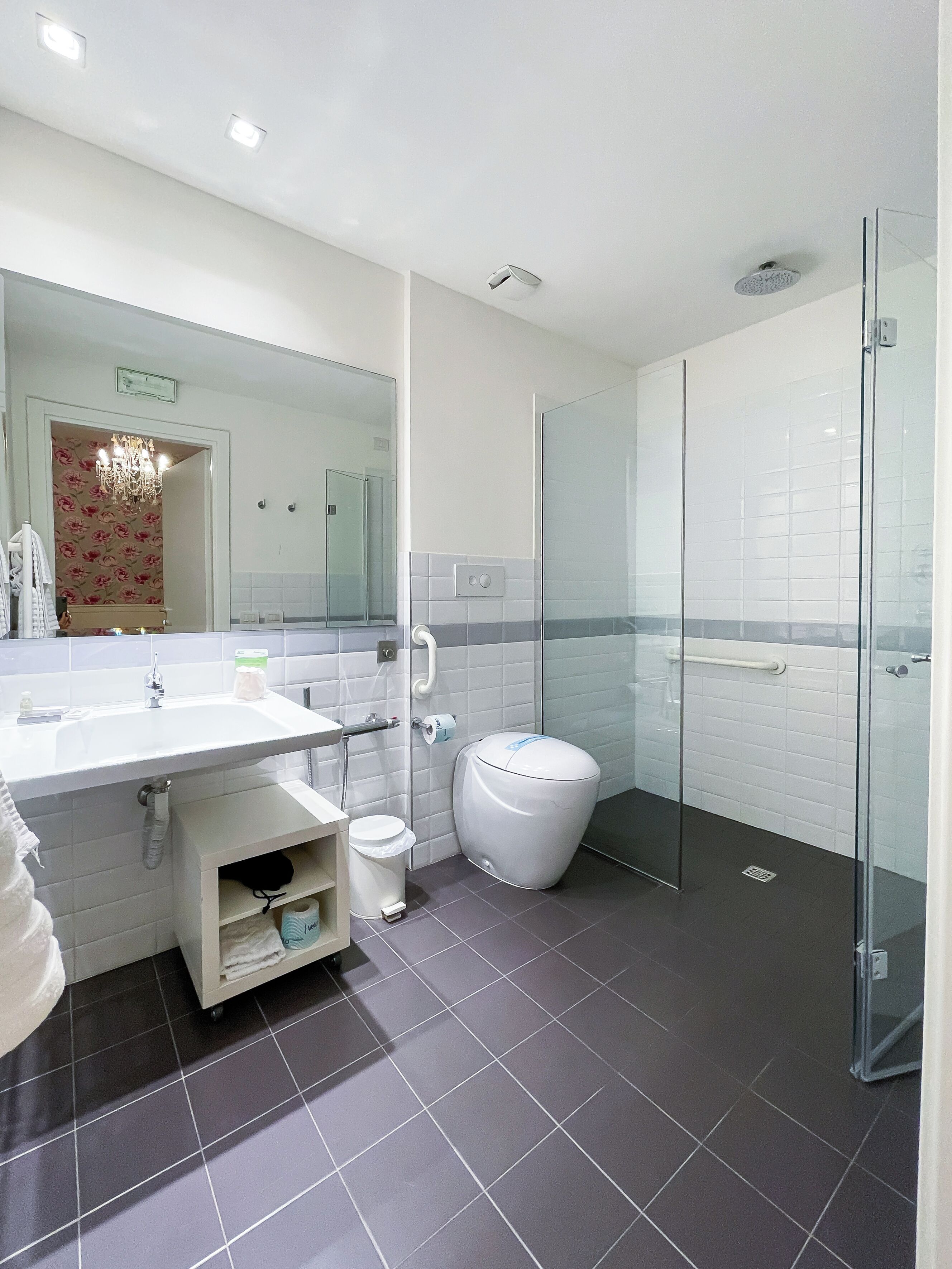 Un baño moderno con cabina de ducha de vidrio, un lavabo blanco y un inodoro.