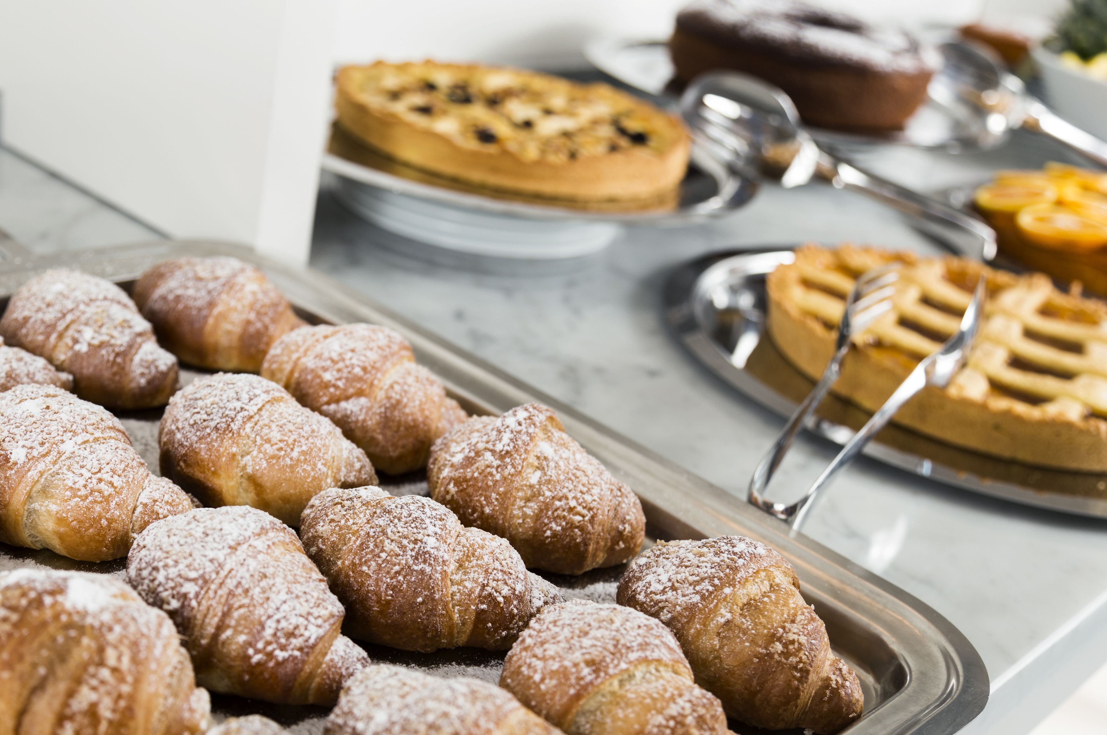 Un bufé con diversas opciones de pastelería, incluyendo cruasanes y una tarta.