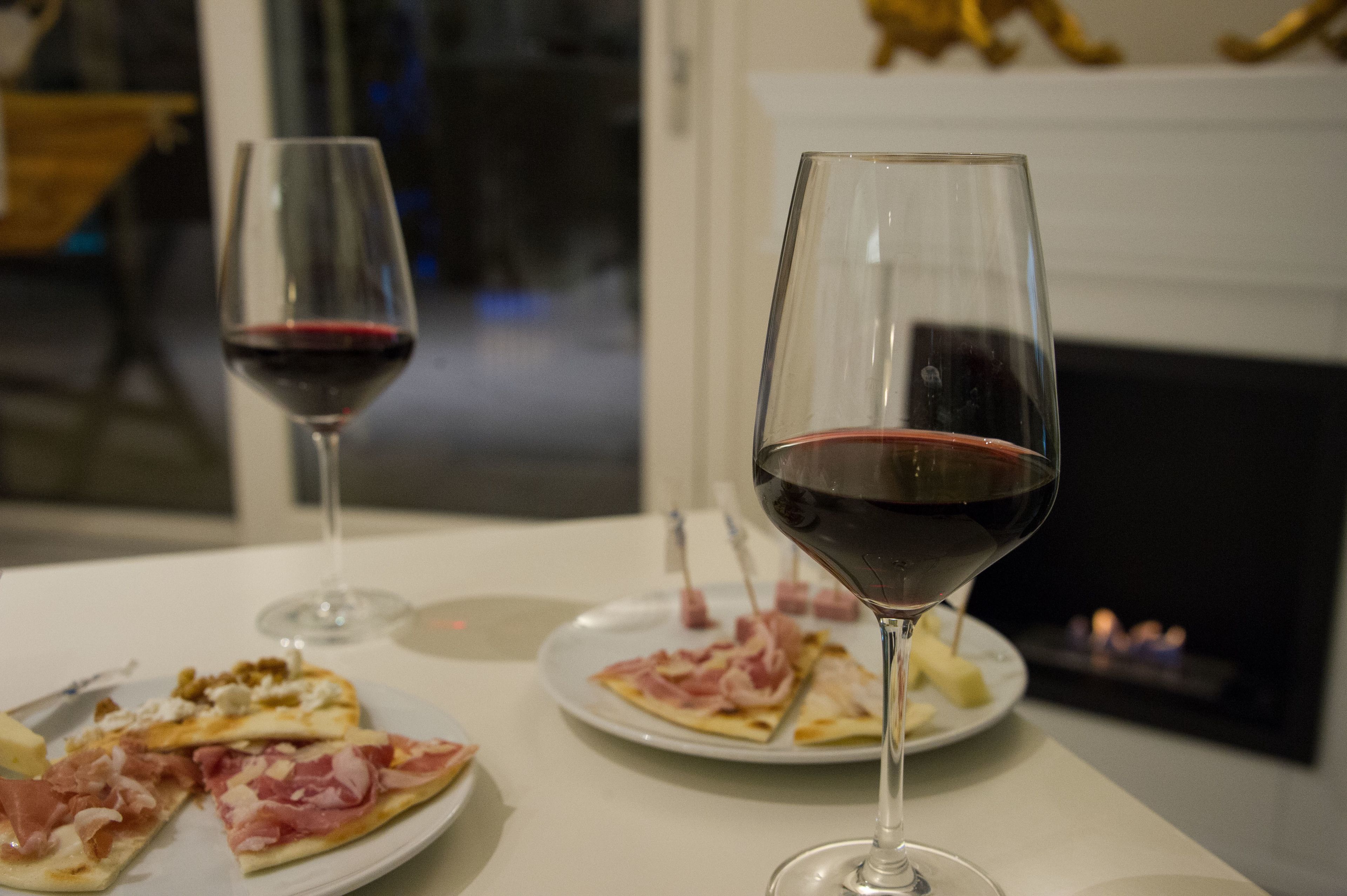 A dining table with two wine glasses and slices of pizza.