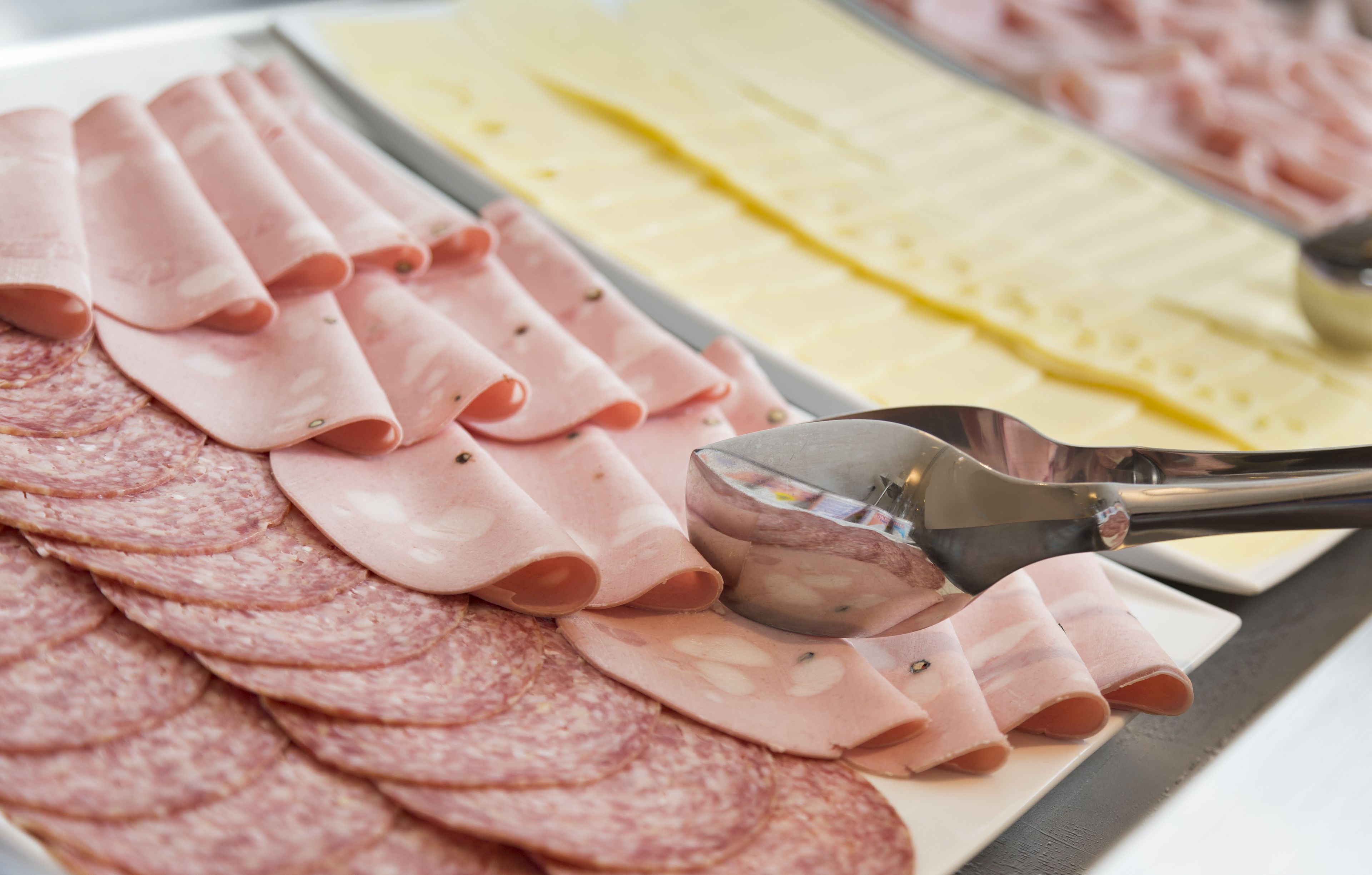A variety of sliced meats on a tray, including salami and ham.