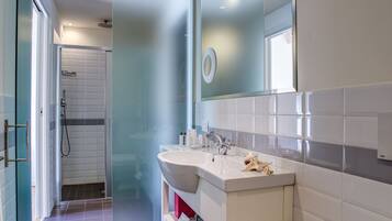 A modern bathroom with a white sink, mirror, and tiled walls.