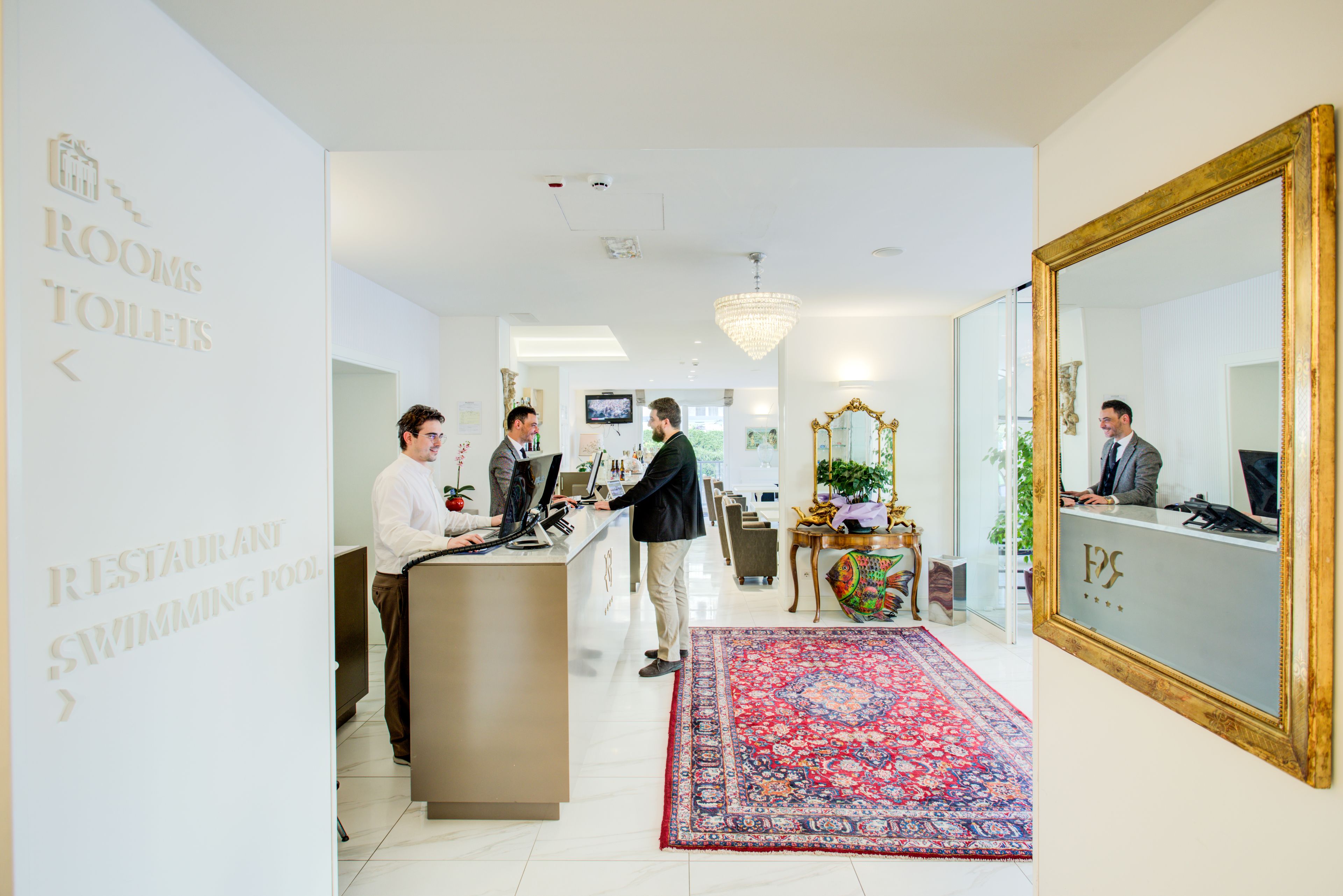 Un hall d’hôtel comprenant un comptoir d’accueil, un grand miroir et un sol recouvert de moquette.