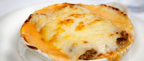 A close-up of a baked dish with melted cheese and a crusty edge, served on a white plate.