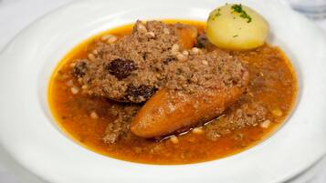 A plate with a meat dish, a boiled potato, and a garnish.