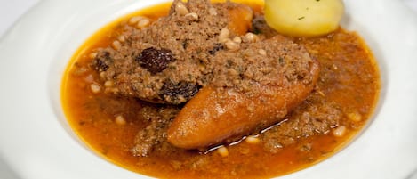 A plate with a meat dish, a boiled potato, and a garnish.