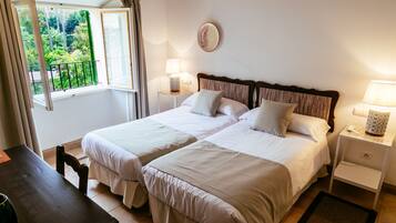 Une chambre avec un grand lit pour deux personnes, deux tables de chevet, une fenêtre avec des rideaux et une vue sur la verdure.