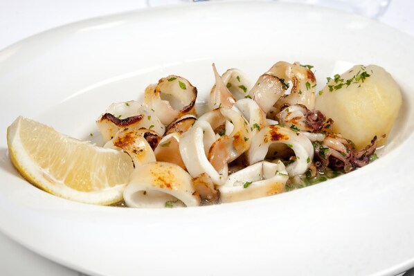 Une assiette de calamars grillés, servis avec du citron et des herbes.