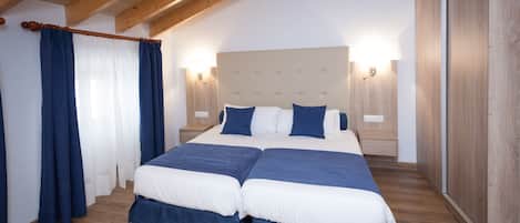 Un lit double avec une literie bleue et blanche, une tête de lit en bois et des lampes de chevet.