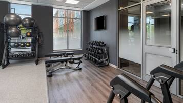Un gimnasio moderno con equipo de ejercicio, ventanas amplias y una televisión de pantalla plana.