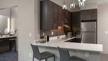 Una cocina moderna con armarios de madera oscura, electrodomésticos de acero inoxidable y una isla central con taburetes.