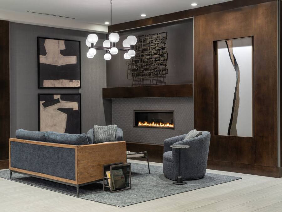 Ein modernes Wohnzimmer mit Sofa, Sessel, Kamin, abstrakter Kunst und einer besonderen Leuchte.