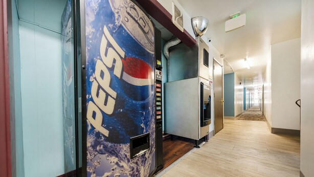 Un couloir avec un distributeur automatique de Pepsi, un réfrigérateur et un four à micro-ondes.