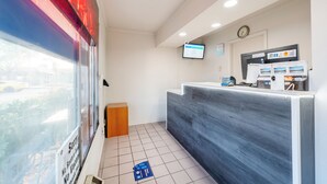 Un espace d’accueil au design moderne, comprenant un comptoir d’accueil, un écran numérique et une horloge murale.