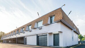 Un bâtiment moderne doté d’un toit en pente, de plusieurs portes de garage et d’une série de fenêtres sur le dernier étage.