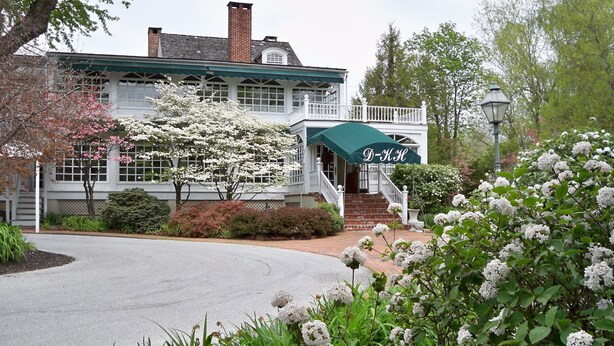 A two-story building with a green awning and a white fence.