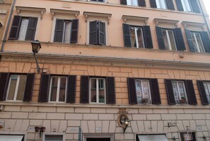 Un edificio de varios pisos con fachada color crema, numerado 40 y 41, que presenta contraventanas tradicionales y una farola.