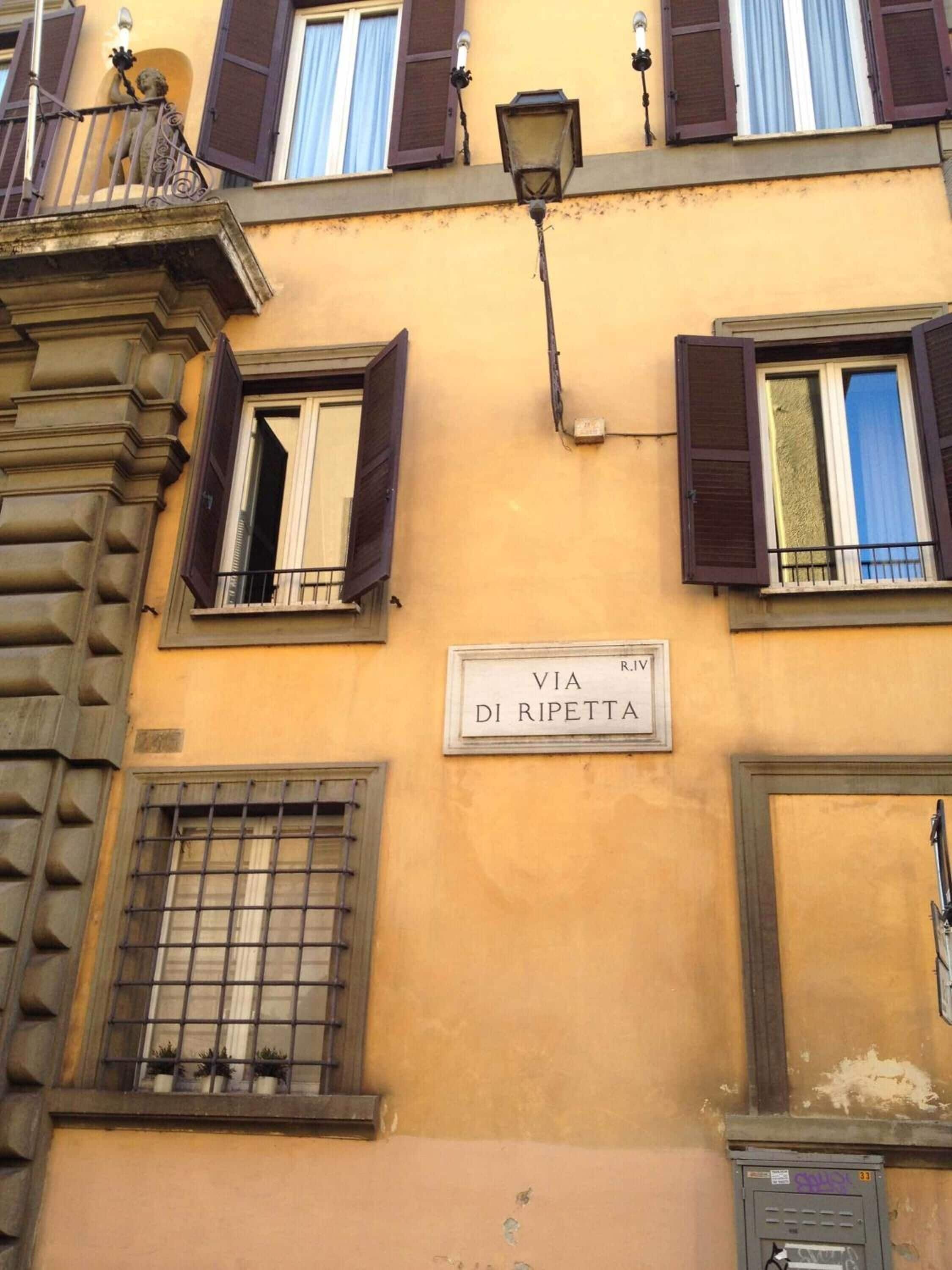A building facade with a street sign reading "VIA DI RIPETTA" and multiple windows with shutters.