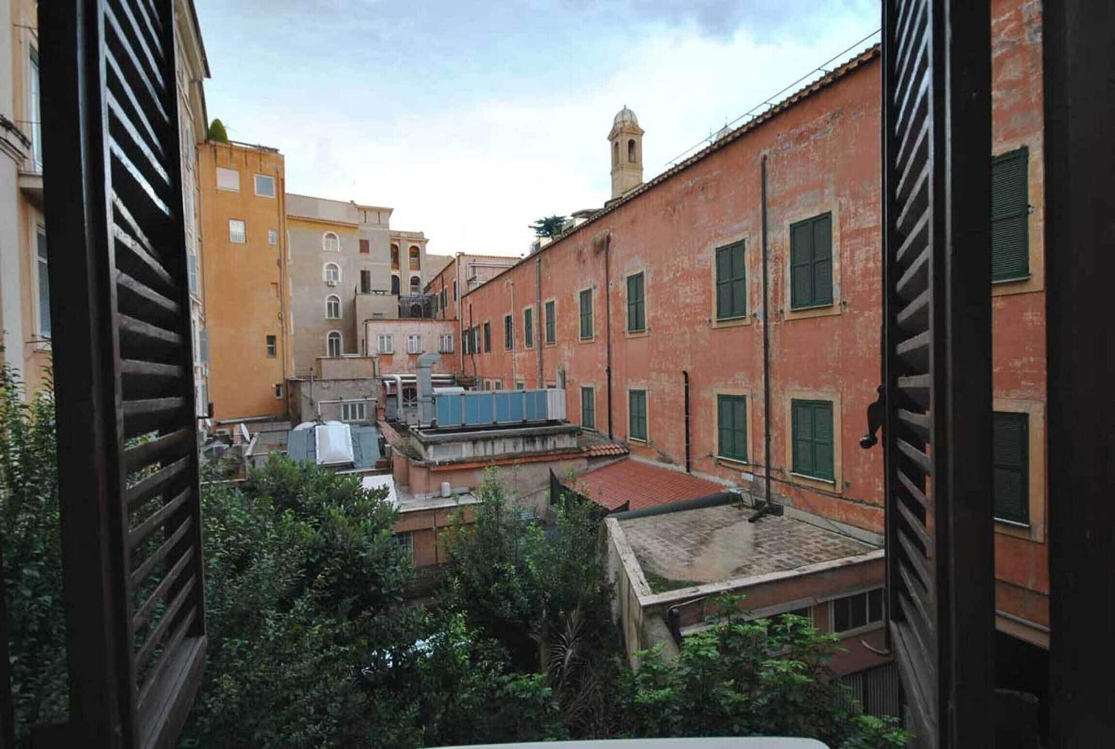 Une ruelle étroite bordée de bâtiments des deux côtés, présentant un mélange de styles architecturaux et quelques touches de verdure.