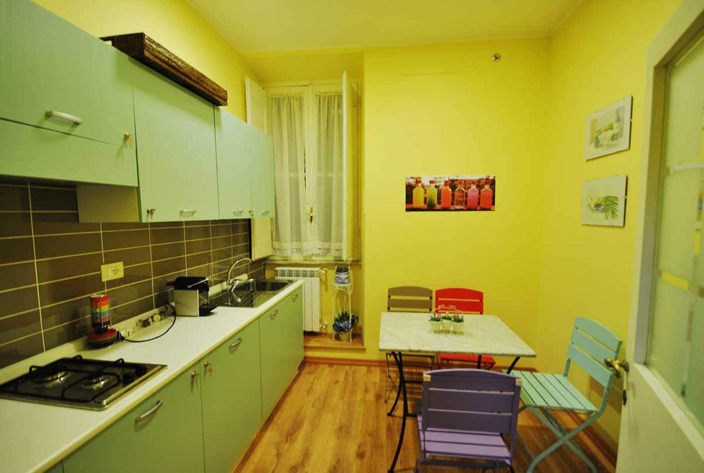 A compact kitchen with green cabinets, a stove, and a dining area with a table and chairs.