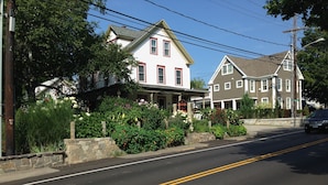 A two-story building with a porch and a stone wall. - Scotch Hill Inn (Ogunquit)