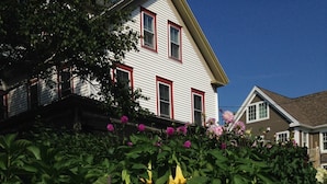 A house with a stone wall and a garden with various plants and flowers. - Scotch Hill Inn (Ogunquit)