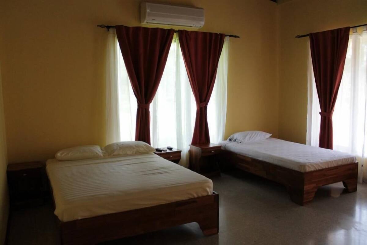 A room with two wooden beds, a nightstand, and an air conditioning unit.