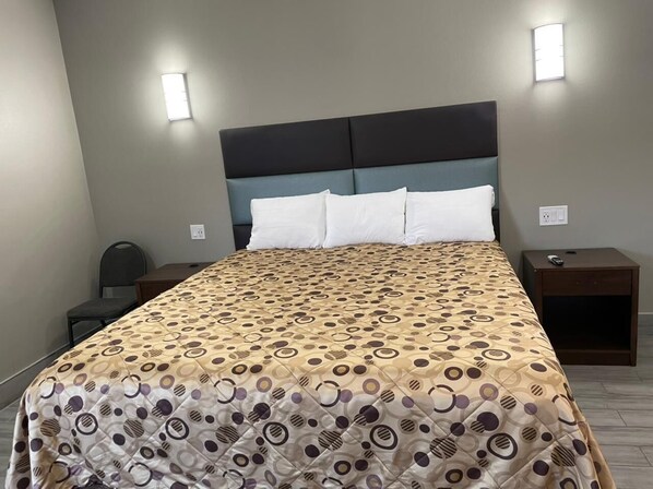 A neatly made bed with a patterned bedspread, two bedside tables, and wall-mounted lights. - Town House Motel (Lynwood)