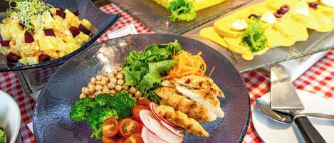 A buffet with various dishes including salads, grilled chicken, and a cake.
