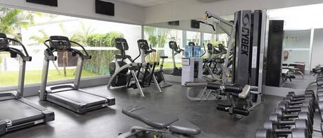 A gym with treadmills, weight machines, and dumbbells.